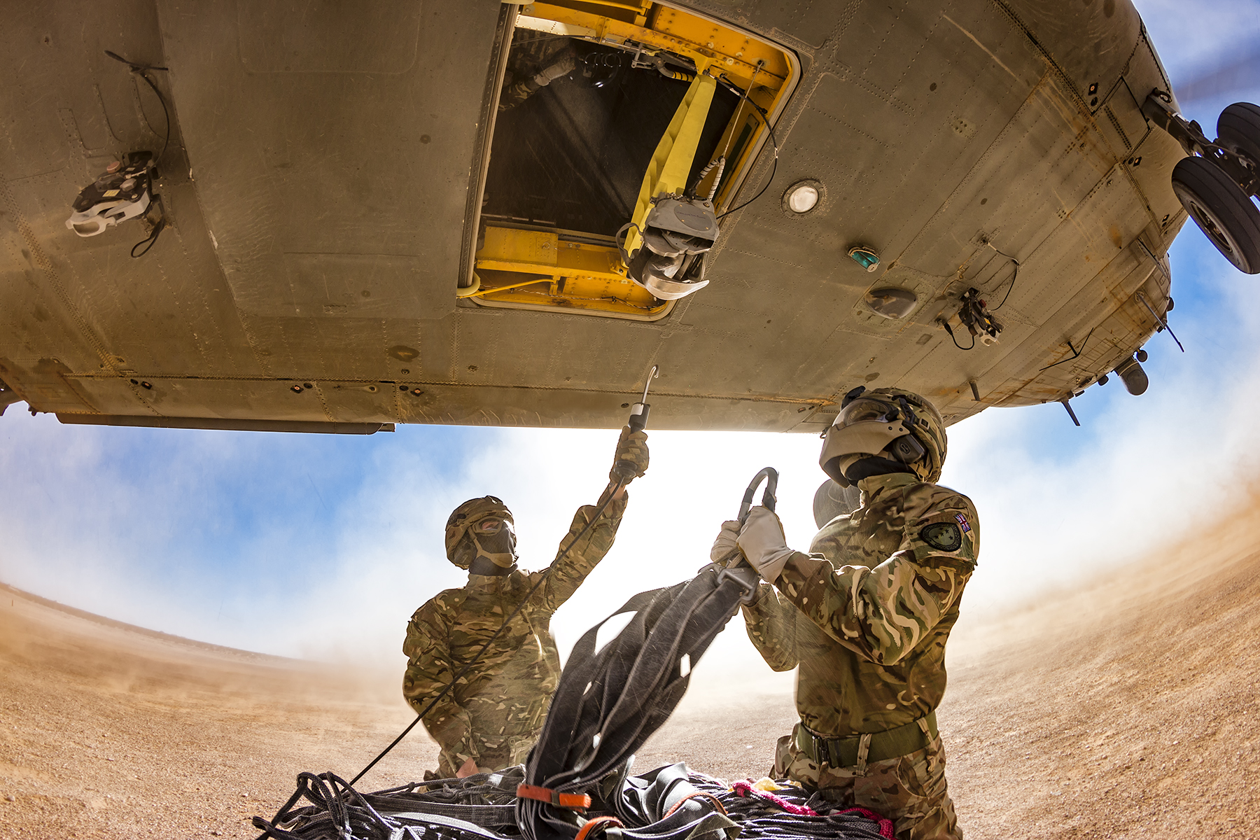 Image shows RAF Regiment hooking load to underslung cargo of helicopter.